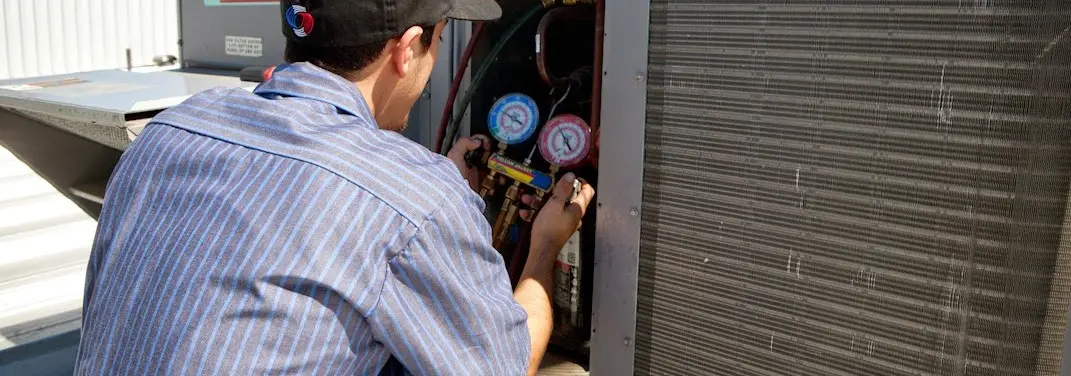 HVAC technician servicing a condenser unit in Olney
