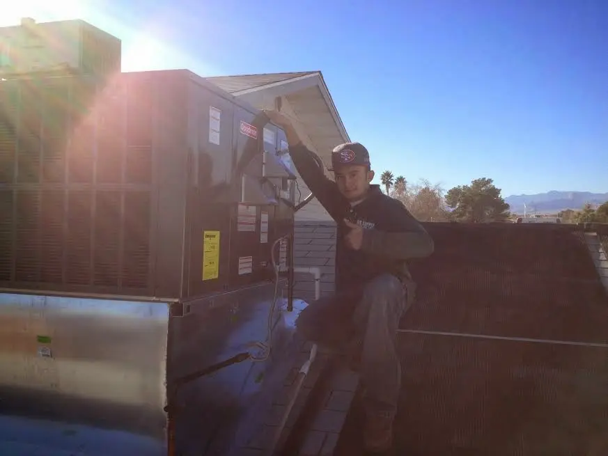 HVAC technician performing Air Duct Repair on a rooftop unit in Olney